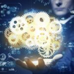 A hand holding a set of gold cogs with a futuristic background.