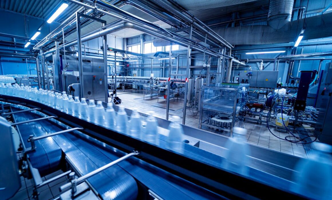 A factory scene. New bottles are lined up along a conveyor belt.